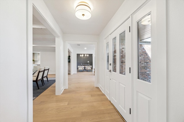 corridor featuring light wood-type flooring and baseboards