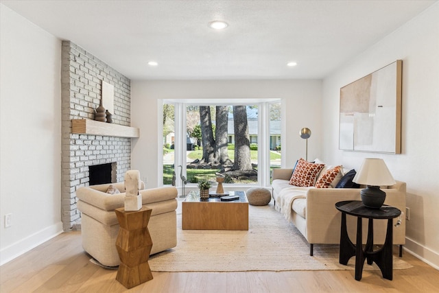 living room featuring a brick fireplace, recessed lighting, wood finished floors, and baseboards