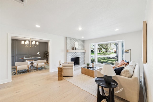 living room featuring baseboards, an inviting chandelier, wood finished floors, and a fireplace