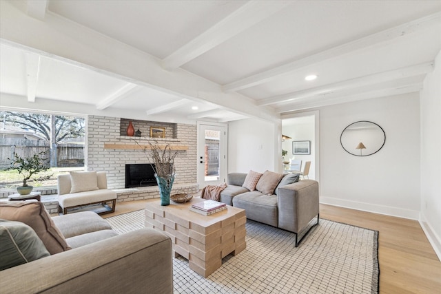 living area with beamed ceiling, baseboards, a fireplace, and light wood finished floors