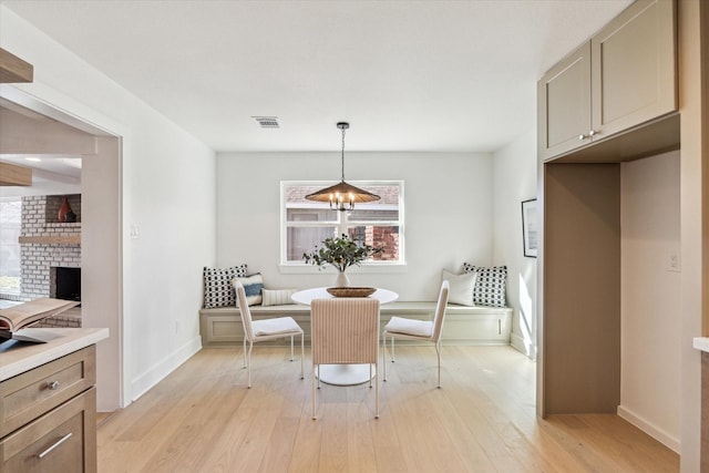 dining room featuring baseboards, visible vents, light wood-style floors, breakfast area, and a chandelier