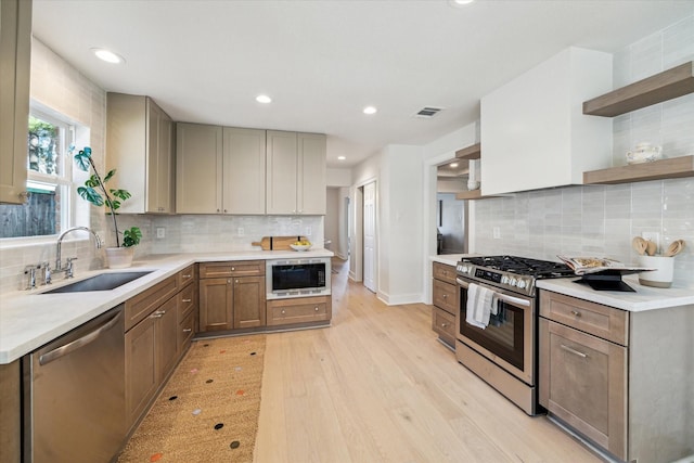 kitchen featuring visible vents, a sink, open shelves, light wood-style floors, and appliances with stainless steel finishes