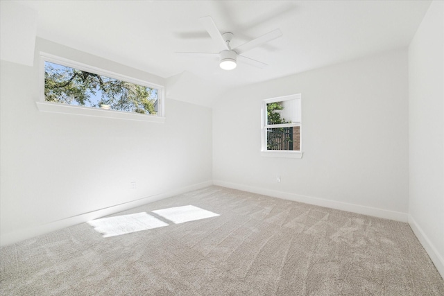 carpeted empty room featuring baseboards, plenty of natural light, a ceiling fan, and vaulted ceiling