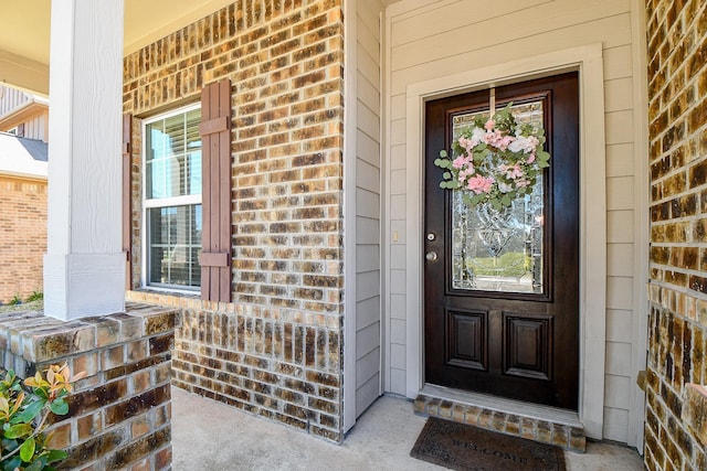 entrance to property with brick siding and a porch