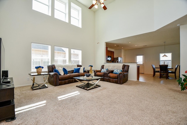 living room featuring plenty of natural light, light colored carpet, and ceiling fan