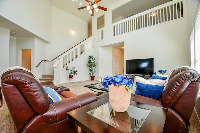 carpeted living room featuring stairway, baseboards, a high ceiling, and ceiling fan