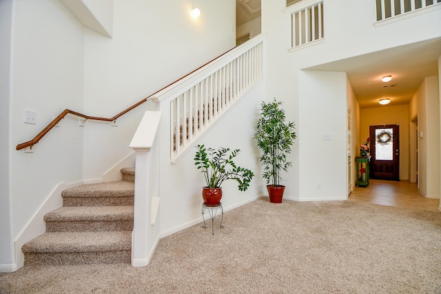 stairway with baseboards, carpet, and a towering ceiling