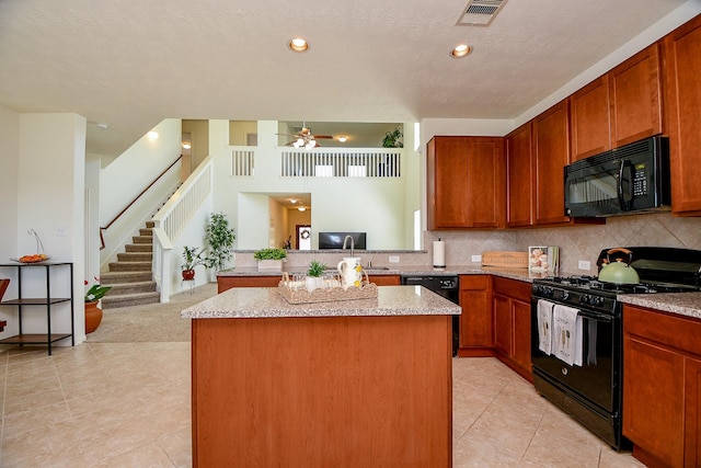 kitchen featuring visible vents, black appliances, light stone counters, tasteful backsplash, and a peninsula