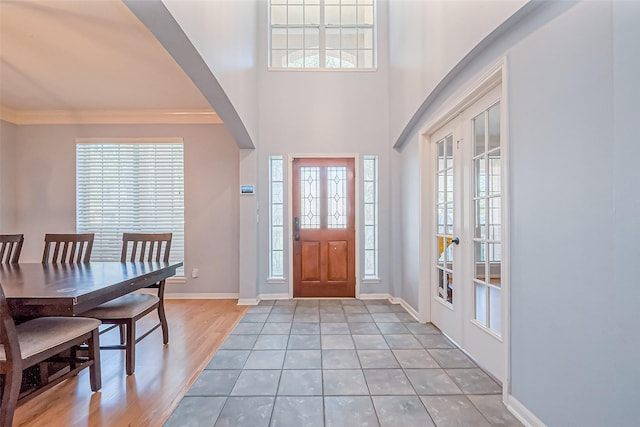 foyer featuring french doors, baseboards, light wood-style flooring, and crown molding