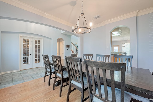 dining area with visible vents, an inviting chandelier, arched walkways, french doors, and crown molding