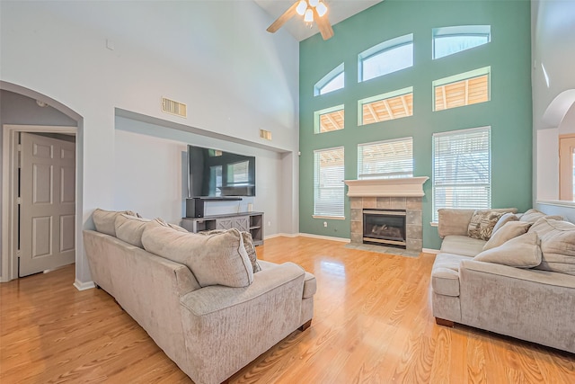 living room with visible vents, arched walkways, light wood-style floors, baseboards, and ceiling fan