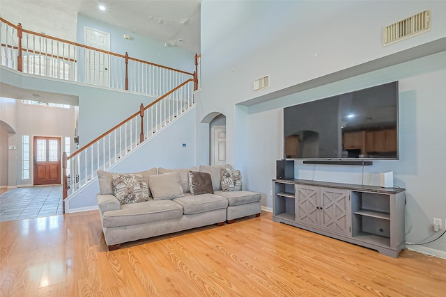 living area featuring stairs, wood finished floors, visible vents, and arched walkways