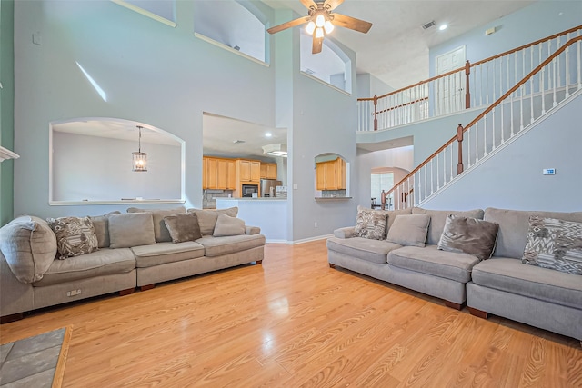 living room with visible vents, baseboards, ceiling fan, wood finished floors, and arched walkways