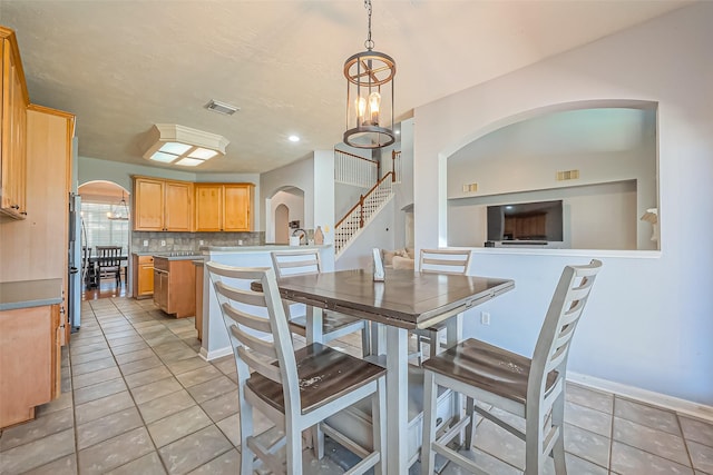 dining area featuring light tile patterned floors, visible vents, and arched walkways