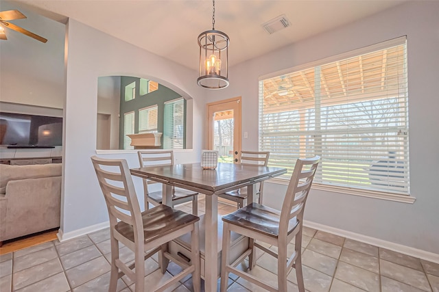 dining area with light tile patterned floors, a ceiling fan, visible vents, baseboards, and arched walkways