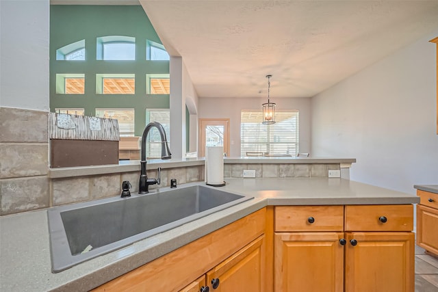 kitchen featuring pendant lighting, light countertops, a peninsula, and a sink