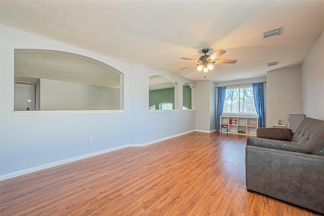 living room featuring visible vents, baseboards, light wood-type flooring, and a ceiling fan