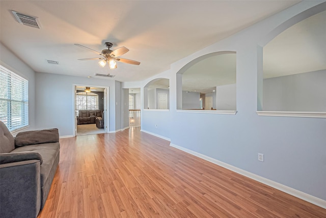 living room with baseboards, visible vents, light wood finished floors, and ceiling fan