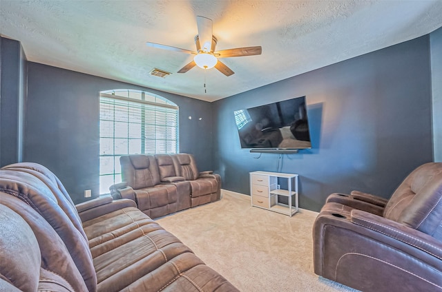 living room featuring carpet flooring, a ceiling fan, visible vents, and a textured ceiling