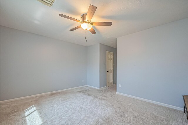 empty room with visible vents, baseboards, light colored carpet, and a ceiling fan