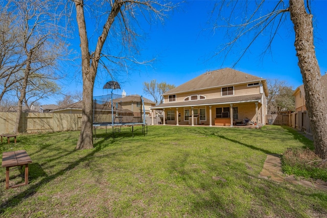 rear view of property featuring a yard, a fenced backyard, and a trampoline