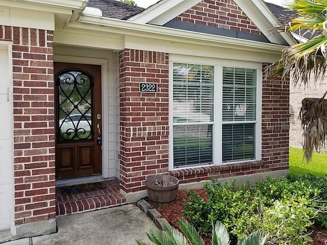 property entrance featuring brick siding and roof with shingles