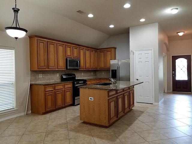 kitchen with dark stone countertops, brown cabinets, appliances with stainless steel finishes, and a sink