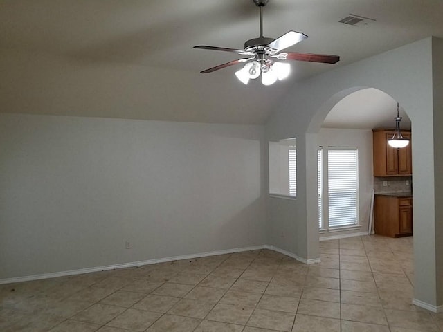 spare room featuring visible vents, arched walkways, light tile patterned floors, ceiling fan, and vaulted ceiling