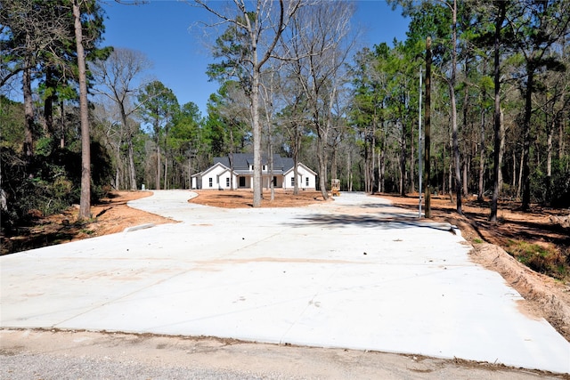 view of front facade with a garage, a wooded view, and driveway