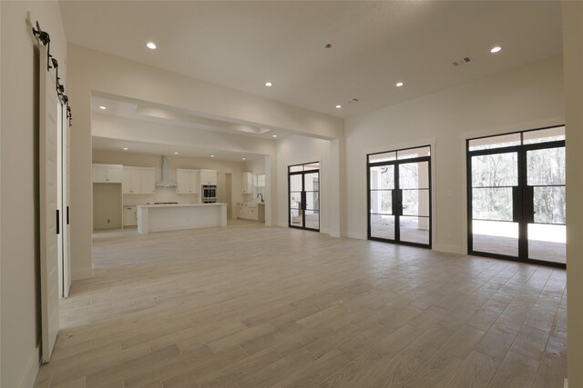 unfurnished living room featuring recessed lighting, french doors, and light wood-style floors