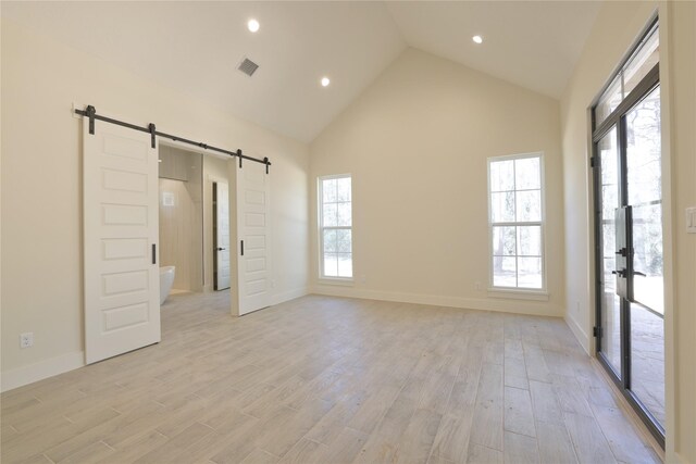 spare room featuring a barn door, plenty of natural light, visible vents, and light wood finished floors