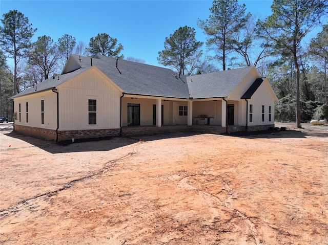 rear view of house with board and batten siding and a shingled roof