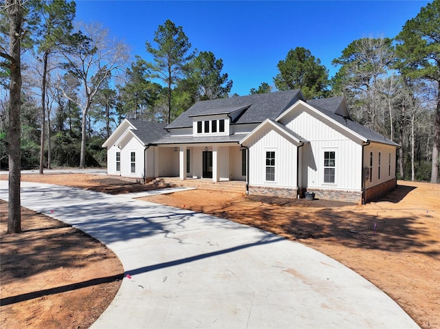 modern inspired farmhouse featuring board and batten siding, driveway, and a shingled roof