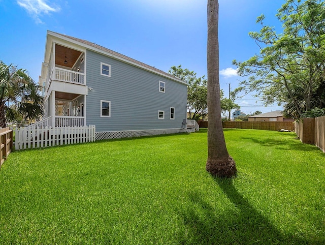 rear view of house featuring a balcony, a yard, and a fenced backyard