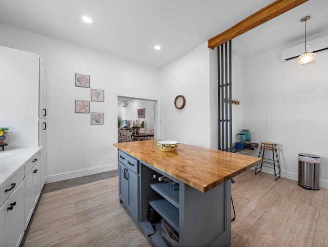 kitchen with recessed lighting, white cabinets, butcher block counters, and a wall unit AC