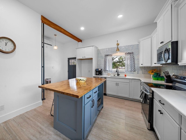 kitchen featuring blue cabinets, butcher block countertops, a sink, white cabinetry, and stainless steel appliances