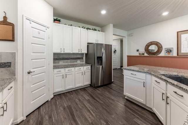 kitchen with stainless steel fridge with ice dispenser, dark wood-type flooring, white cabinetry, light stone counters, and recessed lighting