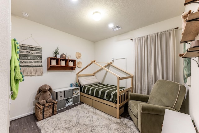 bedroom with wood finished floors, a textured ceiling, and baseboards