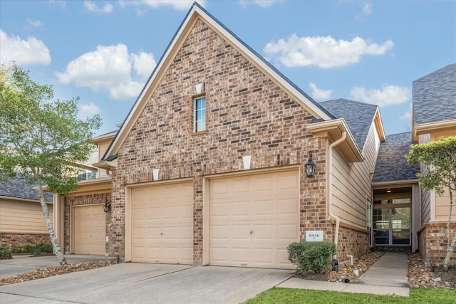 view of front of house featuring brick siding, driveway, and a shingled roof