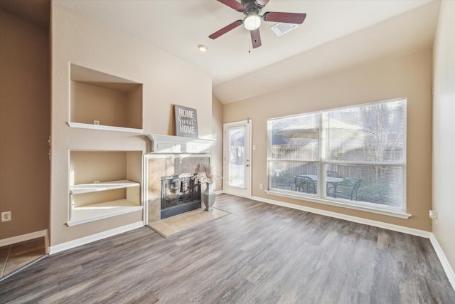 unfurnished living room featuring wood finished floors, visible vents, lofted ceiling, ceiling fan, and a tiled fireplace