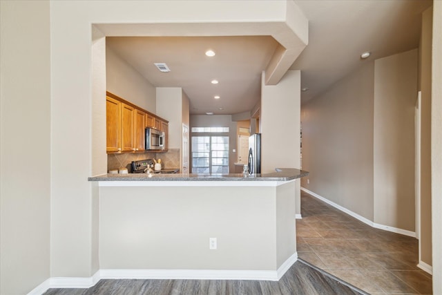 kitchen with visible vents, backsplash, baseboards, brown cabinets, and stainless steel appliances