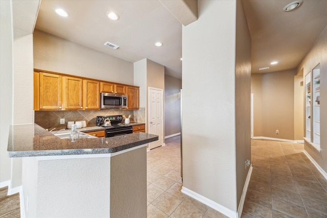 kitchen with stainless steel microwave, black range with electric stovetop, baseboards, light tile patterned floors, and decorative backsplash