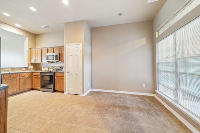 kitchen with visible vents, black electric range, stainless steel microwave, plenty of natural light, and decorative backsplash