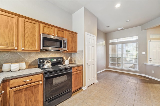 kitchen featuring light tile patterned floors, visible vents, black range with electric cooktop, stainless steel microwave, and tasteful backsplash