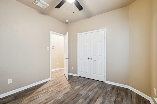 unfurnished bedroom featuring visible vents, ceiling fan, baseboards, wood finished floors, and a closet