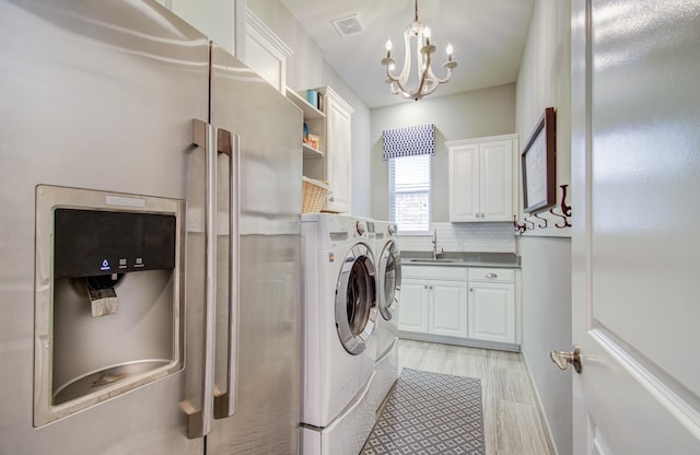 laundry room with visible vents, a notable chandelier, a sink, cabinet space, and separate washer and dryer