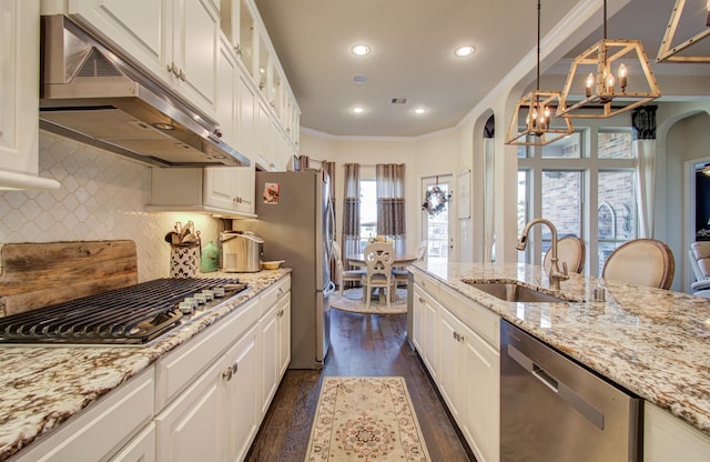 kitchen featuring under cabinet range hood, an inviting chandelier, arched walkways, stainless steel appliances, and a sink