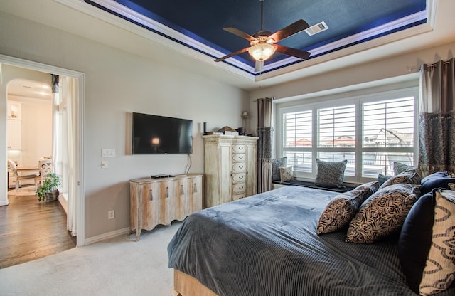 carpeted bedroom featuring visible vents, a tray ceiling, arched walkways, crown molding, and baseboards