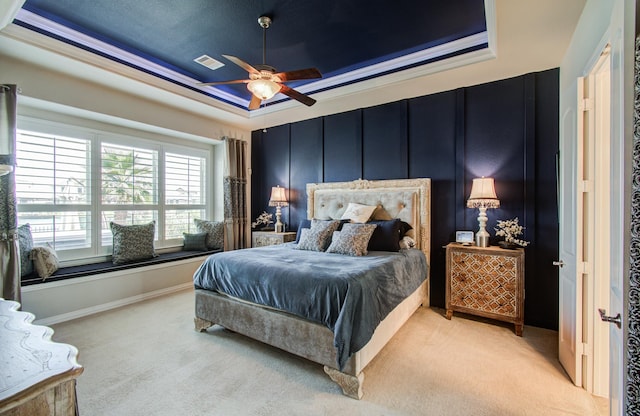 bedroom featuring visible vents, light colored carpet, a tray ceiling, and ceiling fan