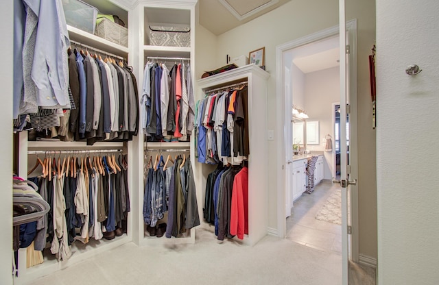 walk in closet featuring attic access and carpet floors